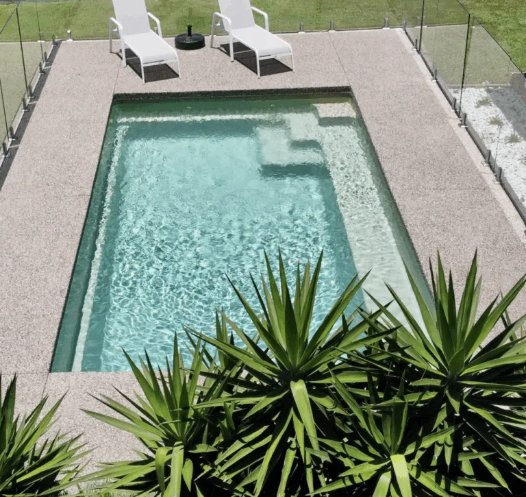 Aerial view of a pale aqua pool surrounded by stone paving and plants